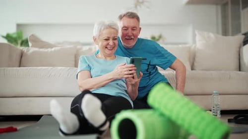 Senior Couple Smiling Looking at Smartphone After Exercise