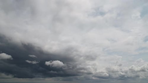 Dark storm clouds move across the blue sky. Time lapse.