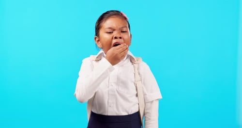 Yawn, sleepy and tired kid in a studio after school in her student uniform with a backpack