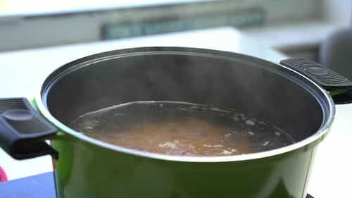 Steaming pot of boiling water on the stove, cooking spaghetti in home kitchen, close up