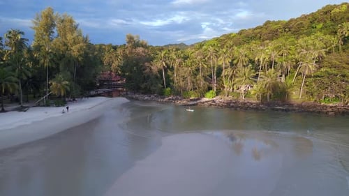 Surfboard paddling. Smooth aerial view flight
evening beach at island koh kood thailand 2022. drone