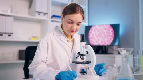 Woman Using Microscope in Lab Wearing Gloves