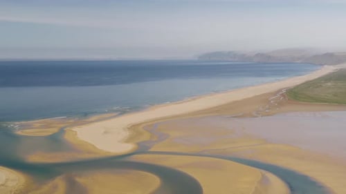 Aerial wide shot of Raudasandur red and sandy beach with river and ocean in background, Iceland