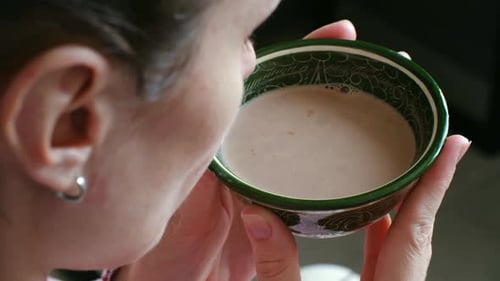 Woman Drinking Warm Milk Tea From a Traditional Bowl