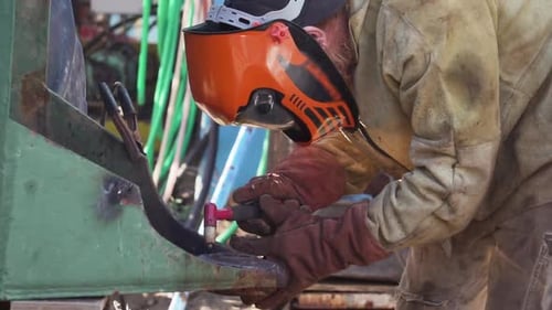 Arc Welder In Full Protective Suit And Mask Welding Steel Structure In A Factory Using Non-Consumabl