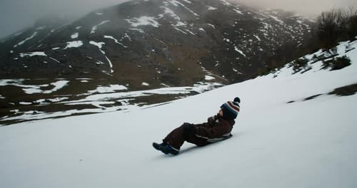 Niños felices y despreocupados deslizándose por el tobogán de la montaña de nieve en vacaciones de invierno