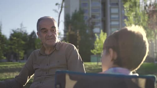 Grandfather and Grandson Talking in a Sunny Park