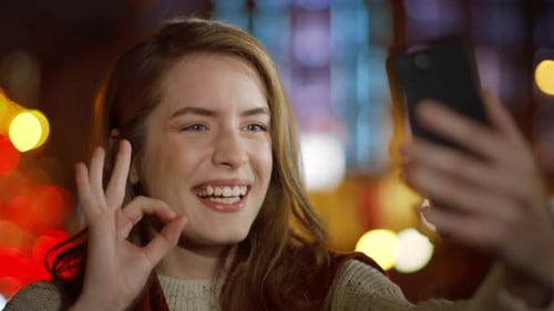 Smiling woman takes selfie at night with lights