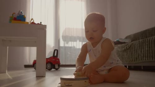 Blond Child Playing Tambourine on Floor at Home