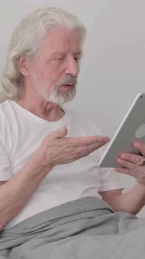Senior Man Video Calling in Bed on Tablet