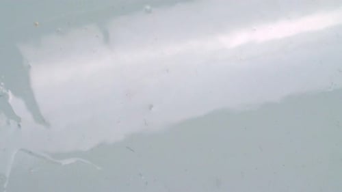 Transparent Liquid Dripping On White Surface. Closeup