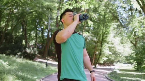 Sporty Athletic Thirsty Japanese Man Runner Jogger Drinking Water After Sport Workout in Park