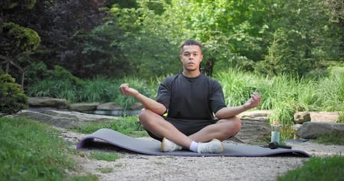 Young African American Spirituality Man Meditating Yoga Asana Sitting in a Park Outdoor