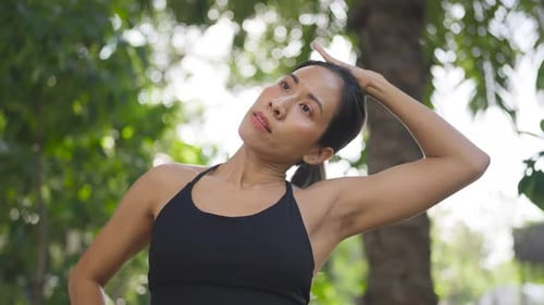Woman strengthens neck muscles in palm garden