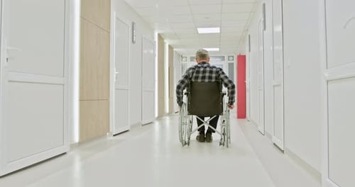 Middleaged Man in Wheelchair in Hospital Corridor