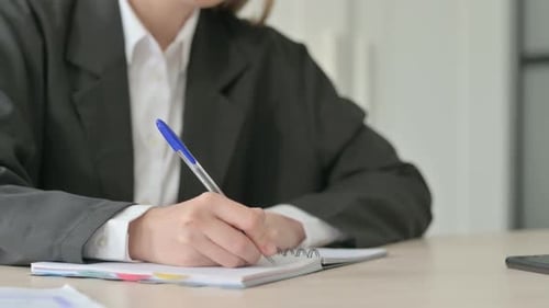 Close Up of Young Businesswoman Writing on Notebook