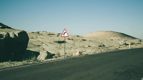 Road Sign Warning of a Curve in the Desert Landscape of Mongolia During Daytime