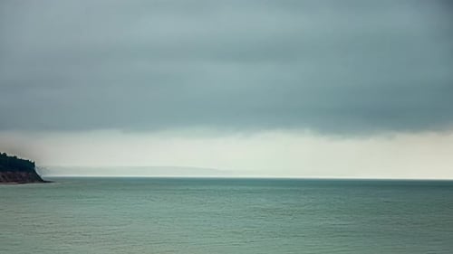 Timelapse shot of dark cloud movement over sea shore on a cloudy day.