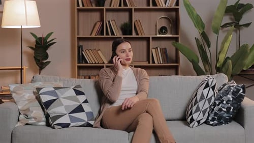 Woman Talking on Phone While Sitting on Sofa