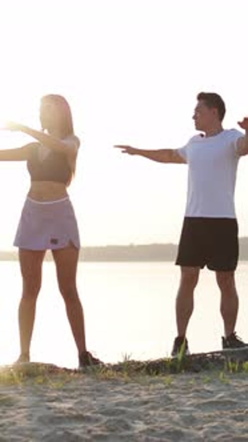Couple Stretching Arms on a Beach at Sunrise