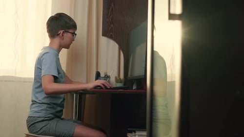 Boy Writes Program Code at Home Using Computer