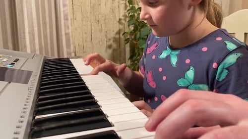 Child Practicing Piano With an Adult Instructor