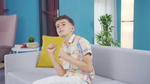 Cheerful boy is dancing on the sofa.