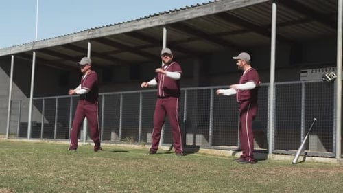 Baseball players warming up on field, stretching arms before game