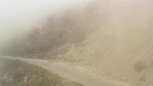 Drone flying backward over an abandoned asphalt mountain road. Aerial view of a mountain road vanis