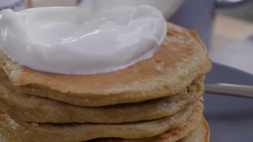Close-up of placing a dollop of yogurt on pancakes.