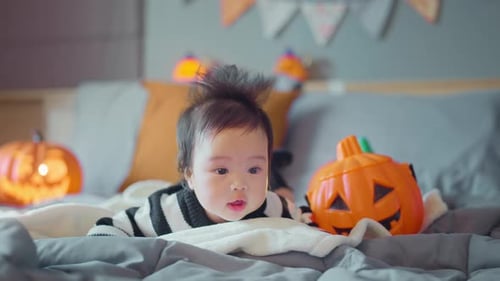 Cute Infant Lying Near Halloween Jack-o-Lanterns