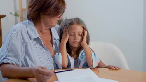 Grandmother and Granddaughter Studying Indoors at a Table
