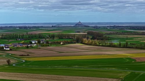 Beautiful green meadows and distant Mont Saint Michel abbey in France