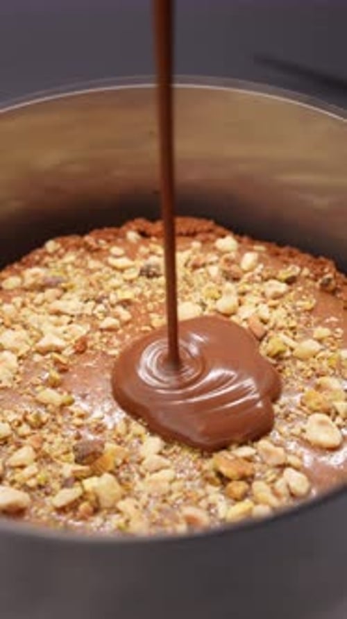 Chocolate being poured over a frosted cake