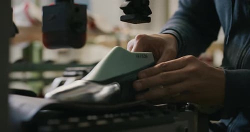 Macro of a shoemaker using a professional machine to bend the shoes and fix them according to the