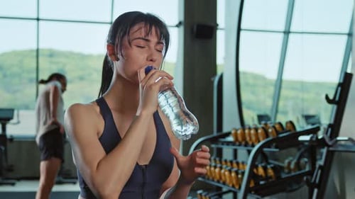 Woman Drinks Water During Gym Workout