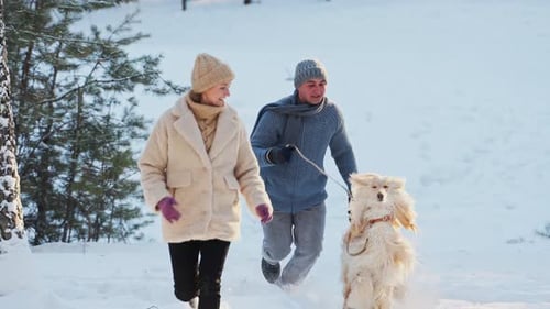 Couple Walk Afghan Hound Dog in Snowy Park