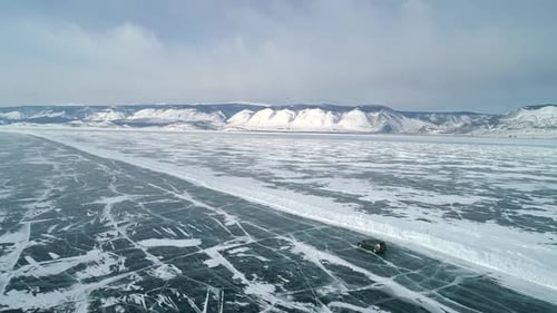 Aerial View on a Car Driving on an Ice Road on Frozen Baikal Winter Landscape of Lake Baikal Drone
