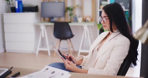 A Confident Businesswoman Works in the Office Counts on a Calculator