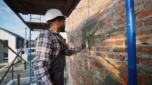 Construction Worker Smoothing Mortar on Brick Wall Outdoors