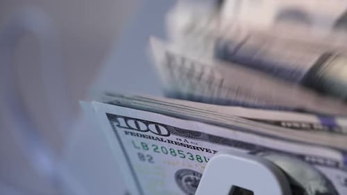 American currency hundred dollar bills falling on the holder of device. Close up.