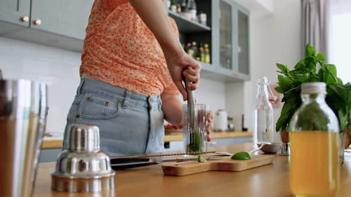 Woman Prepares Mojito Cocktail at Kitchen Counter
