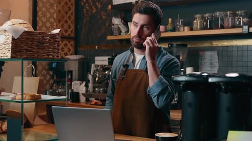 Cafe Owner Works at Counter While Talking on Phone