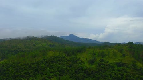 A drone shot advancing towards a majestic tropical mountain range on a moody, cloudy day.