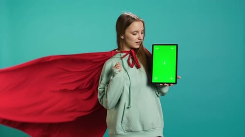 Woman with Red Cape Presenting Tablet with Green Screen