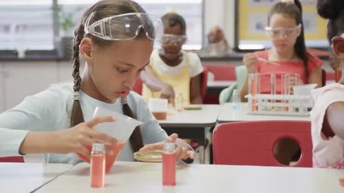 Focused diverse schoolgirls doing experiments in elementary school chemistry class, slow motion
