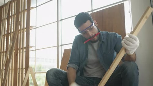 Concentrated Carpenter Marks Wood in Workshop