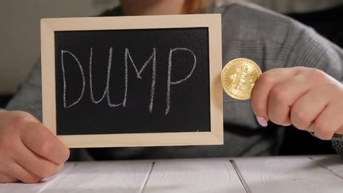 A Woman Holding a Board with the Inscription DUMP and a Golden Bitcoin Coin
