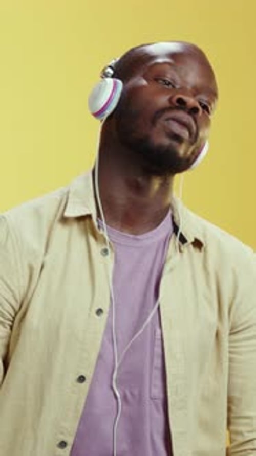 Man Dancing with Headphones in Front of Yellow Background
