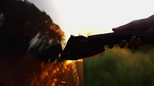 Female Hand Plugging in a Charger to Electric Car Young Woman Plugs Electrical Auto to Charge